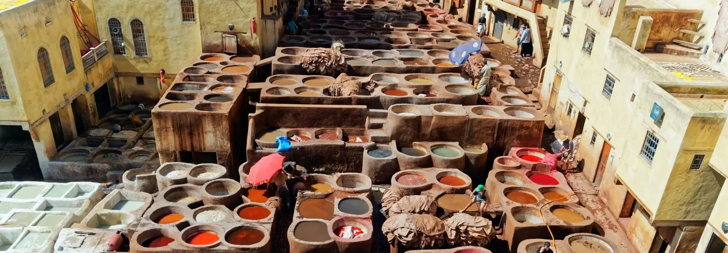 Operai che lavorano nelle storiche concerie di Fes, circondati da coloratissime fosse di tintura, come parte dell'esperienza culturale di un tour di 3 giorni da Fes al deserto